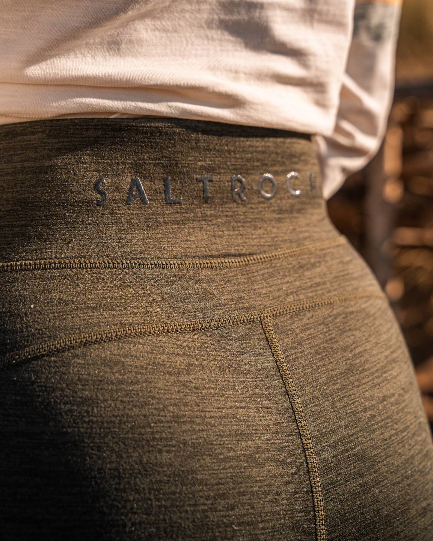 Close-up of a person wearing Saltrock Trek Women's 4 Way Stretch Outdoor Leggings in dark green, featuring a zipped thigh pocket, squat-proof and comfortable 4-way stretch fabric.