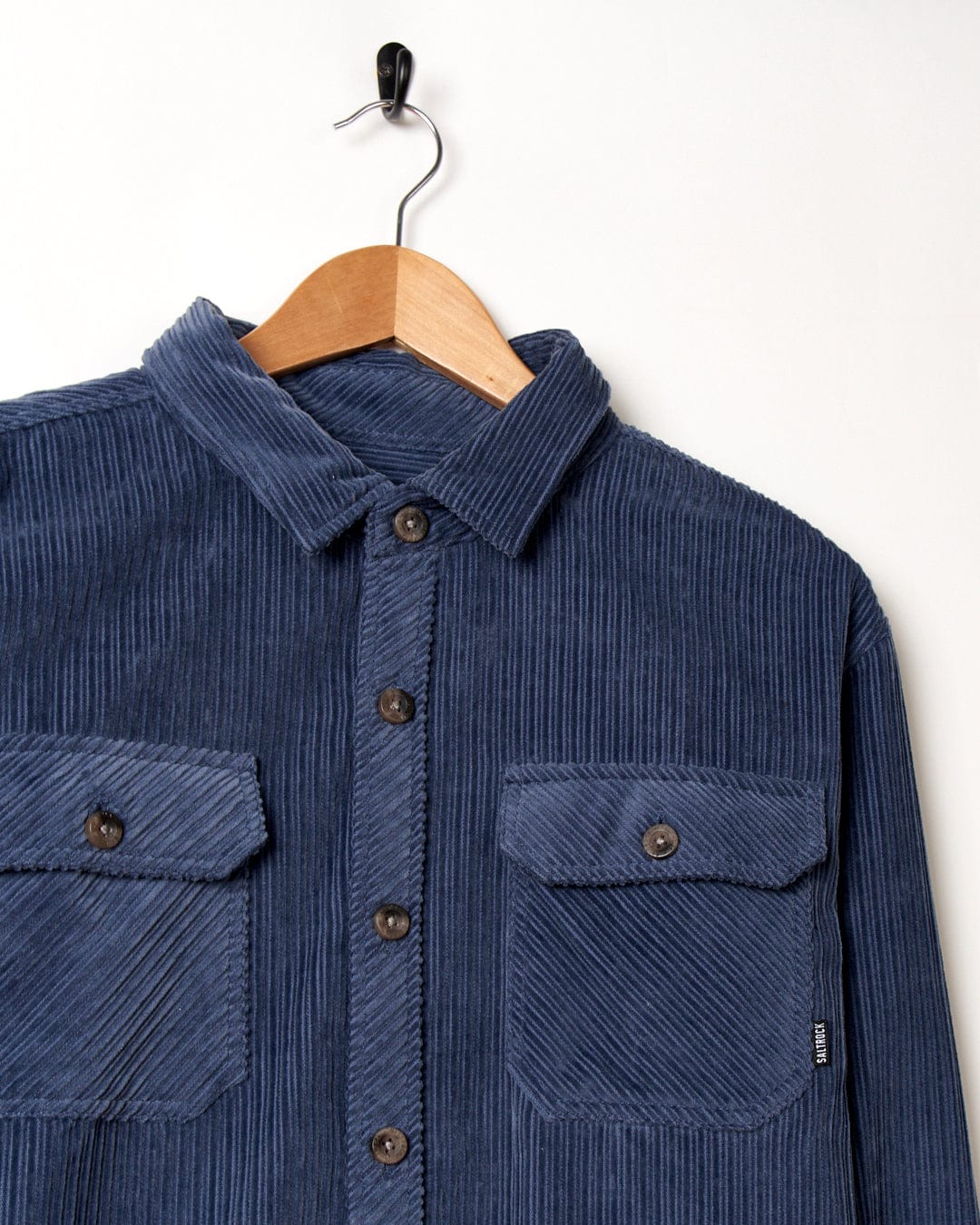 A Saltrock Ace blue corduroy shirt with front chest pockets hanging on a hanger.