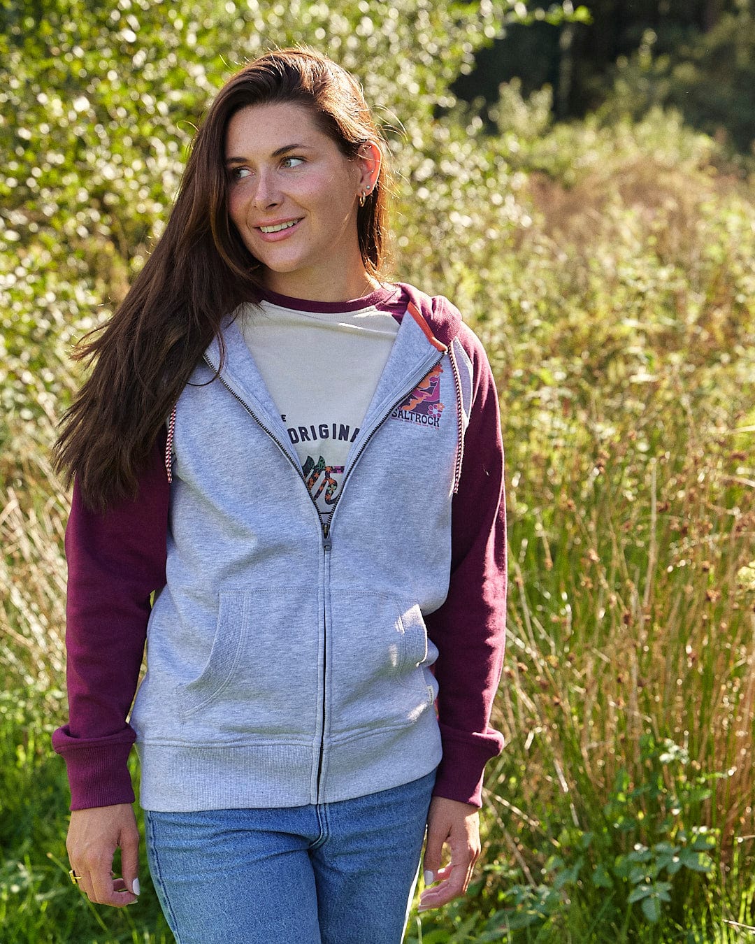 A comfortable woman wearing the Adventure Awaits - Saltrock Womens Zip Hoodie - Light Grey standing outdoors.