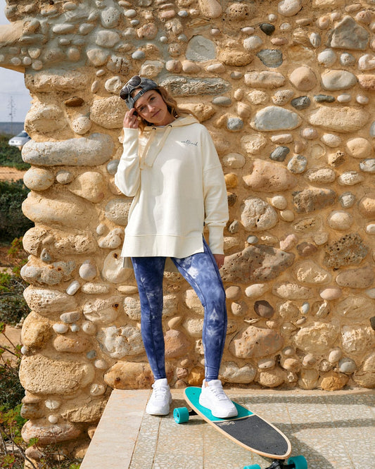 A woman standing next to a stone wall with a Saltrock Ahimsa - Womens Legging - Blue made from high quality materials.