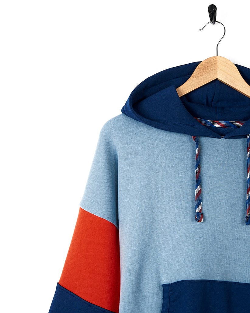 A Saltrock Anya - Womens Pop Hoodie - Blue with contrast paneling hanging on a hanger.