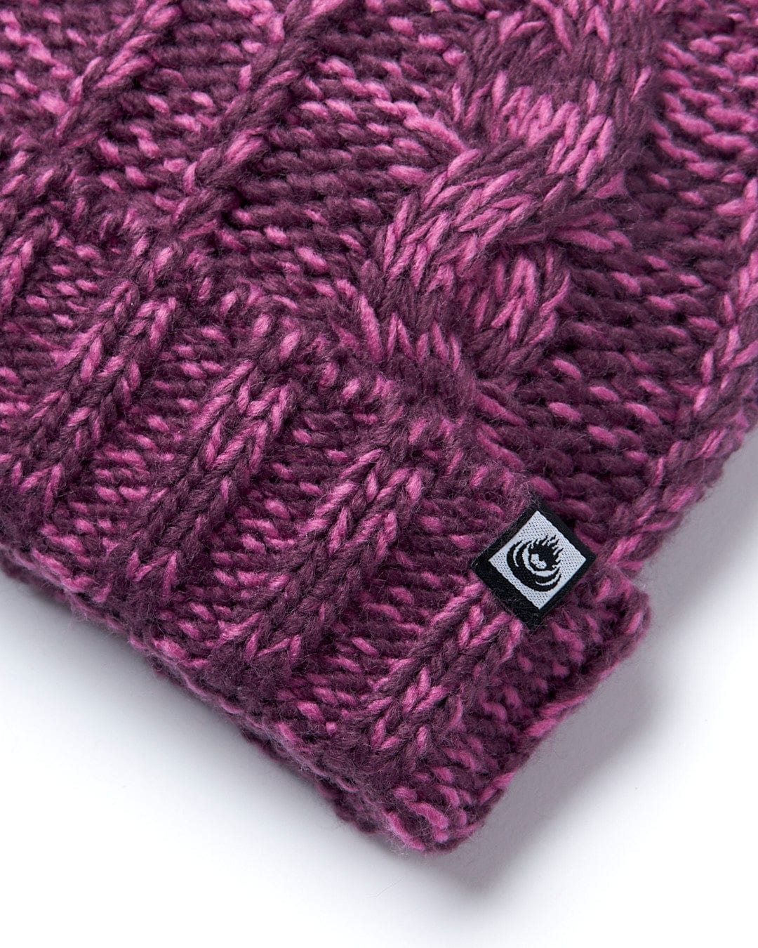 A Twist - Cabled Beanie - Dark Pink by Saltrock on a white surface.