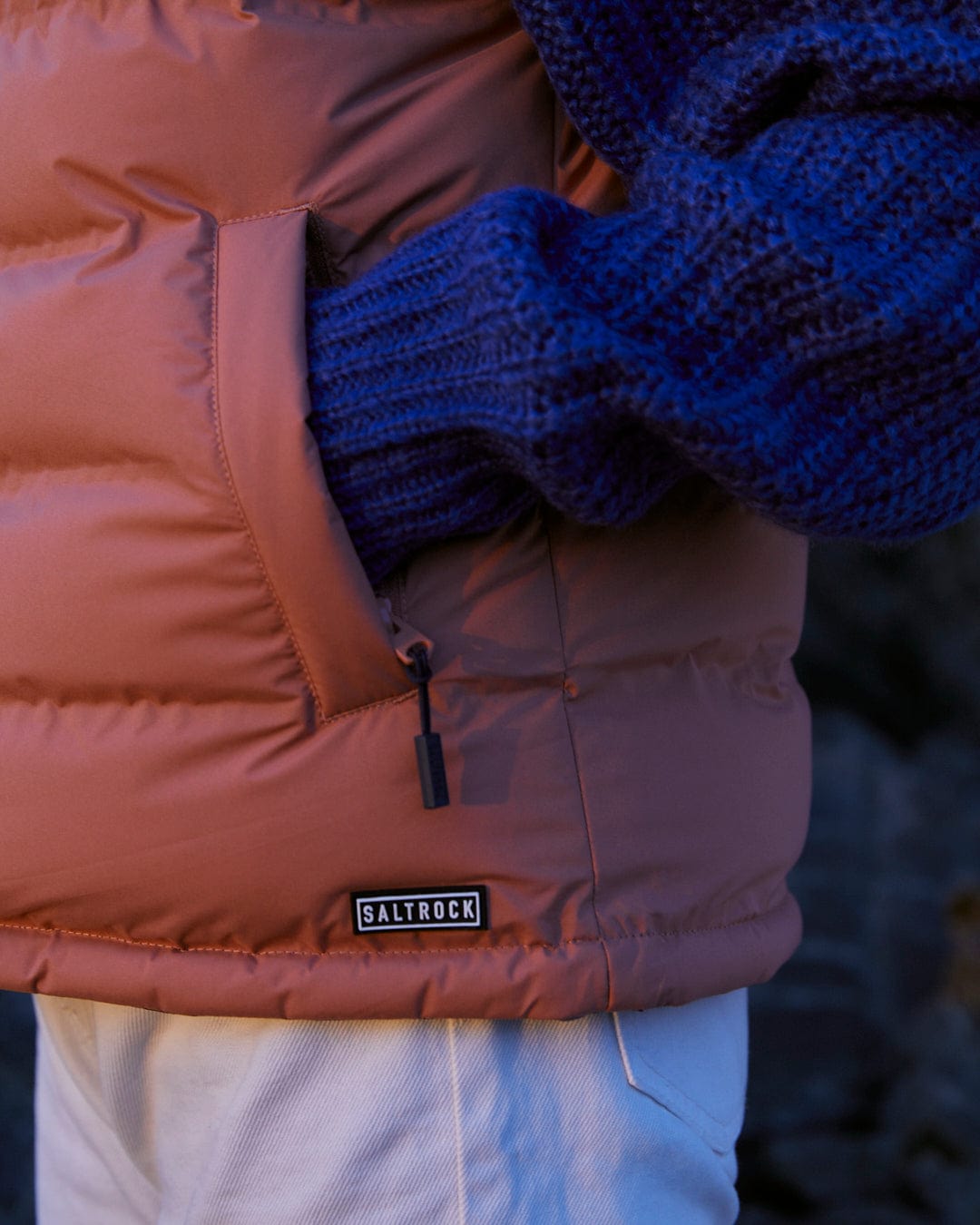 A woman wearing a Saltrock Astra - Womens Reversible Padded Gilet - Blue/Pink with a detachable hood.