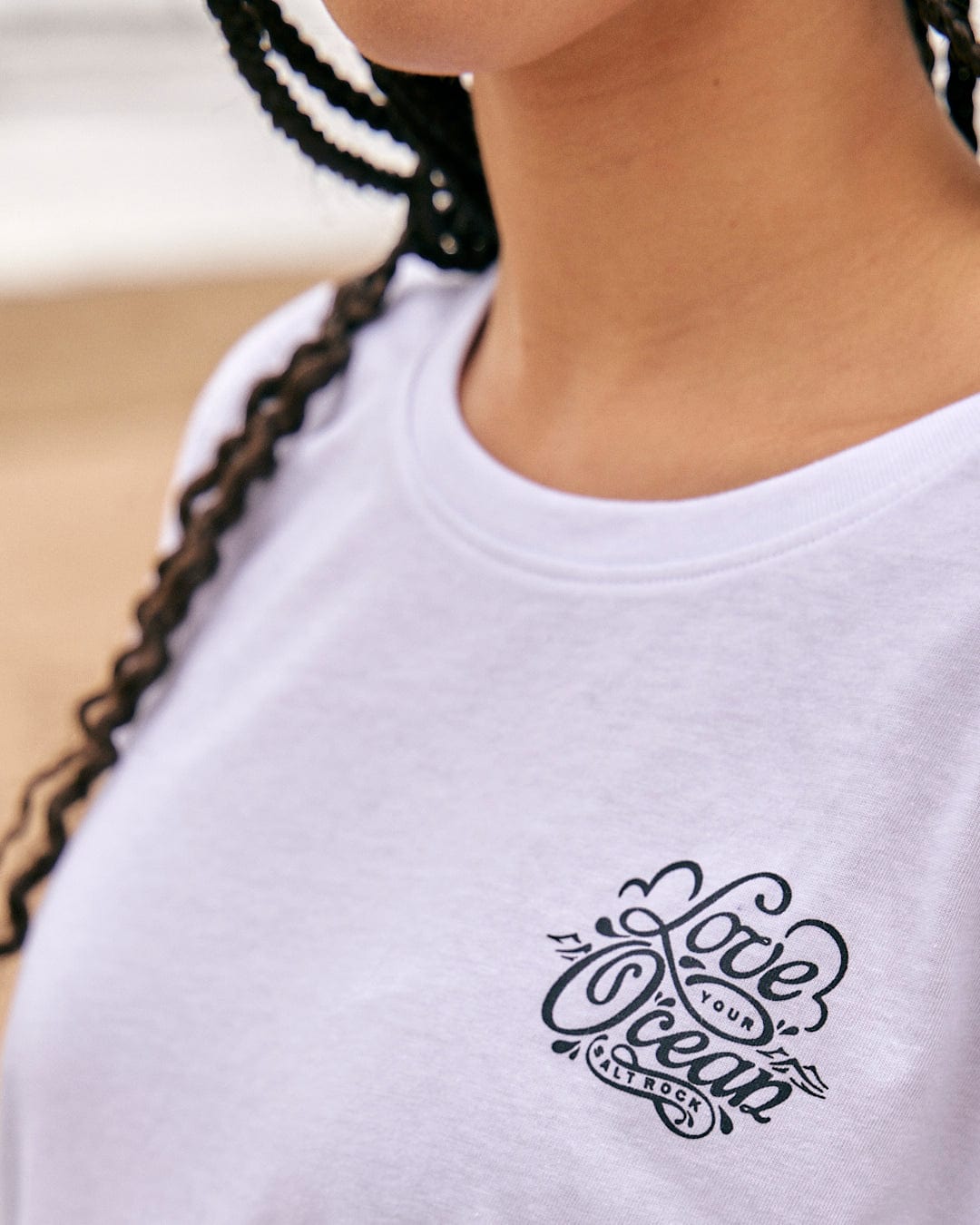 A woman wearing a Saltrock Astra - Womens Short Sleeve T-Shirt - White with a black logo on it.