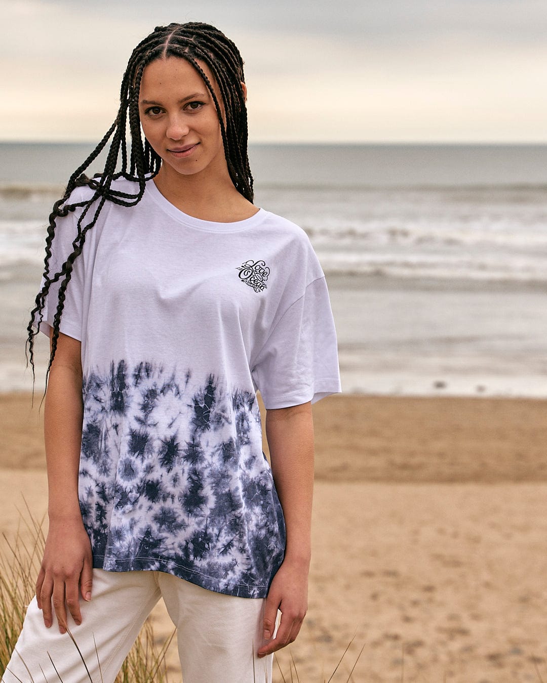 A woman wearing a Saltrock Astra - Womens Short Sleeve T-Shirt - White standing on the beach.