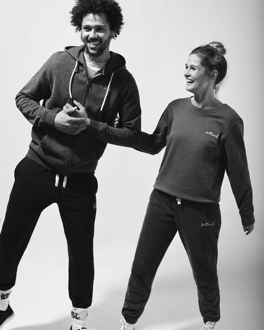 A black and white photo of a man and woman posing for a photo, wearing Saltrock Original - Mens Zip Hoodies in Dark Grey made from a cotton/polyester blend.