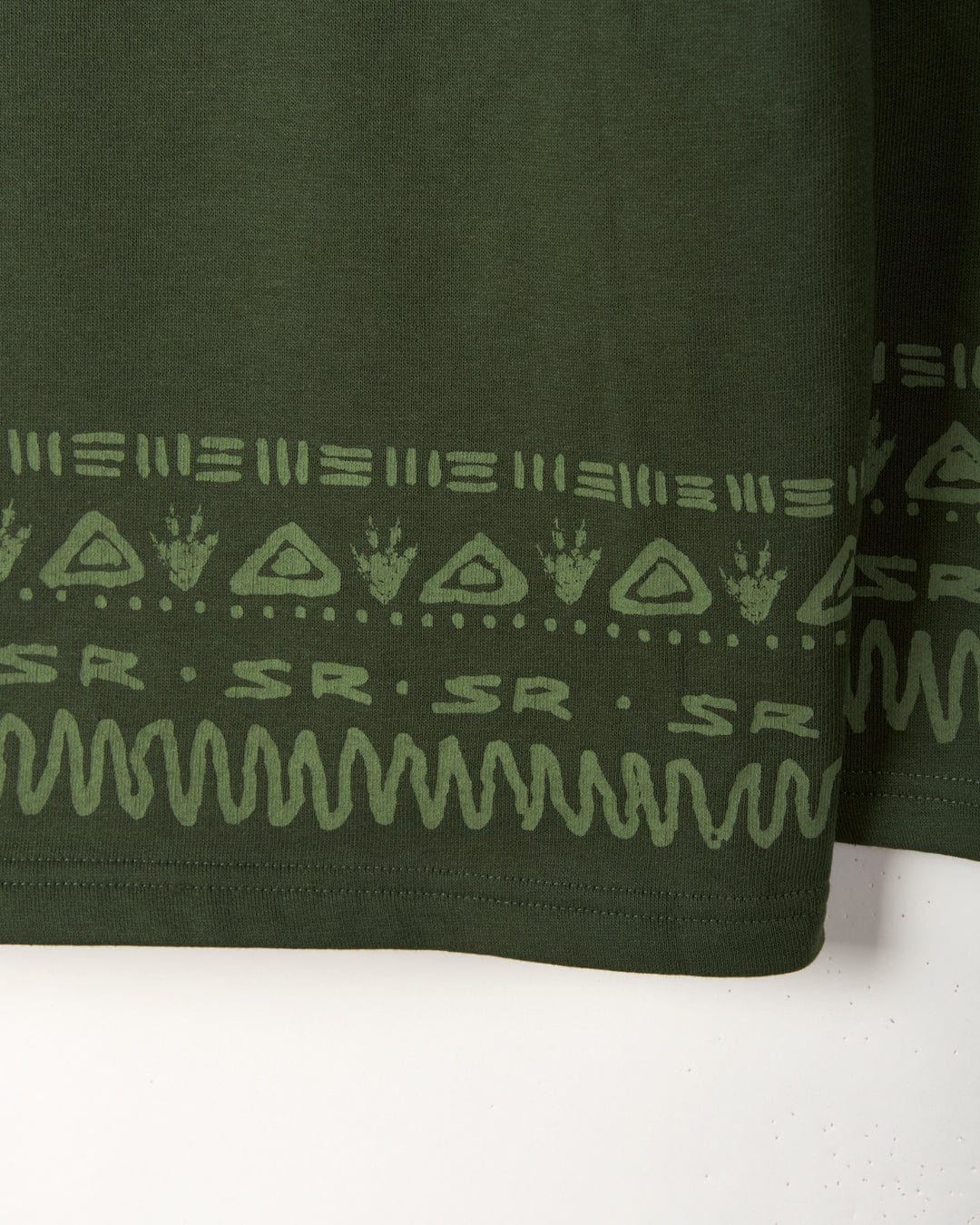 Close-up of a Saltrock Back in the Day - Recycled Kids Pop Hoodie - Dark Green fabric with a decorative white Aztec pattern along the hem.