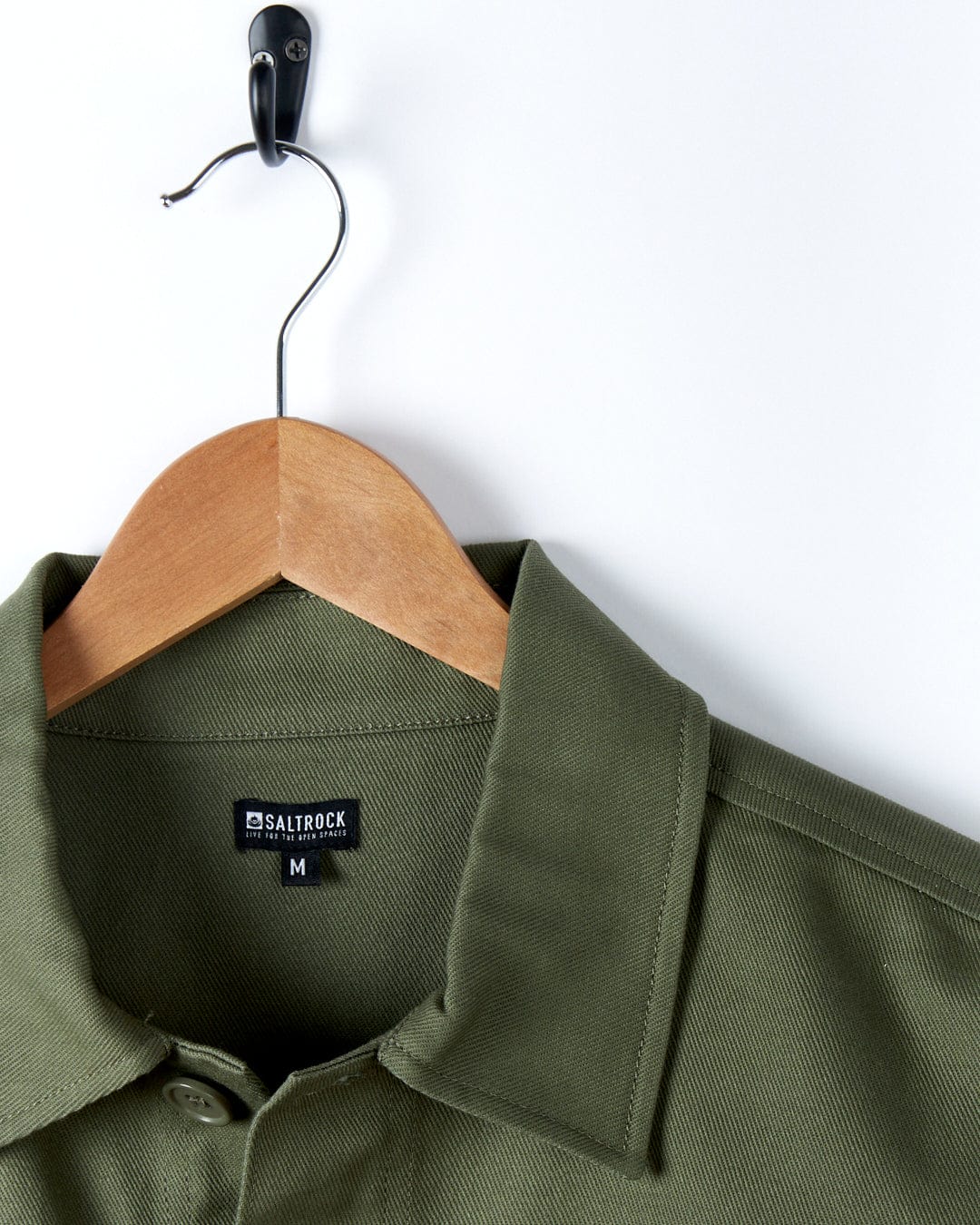 A Saltrock Barden - Womens Lightweight Utility Jacket in Dark Green hanging on a hanger.