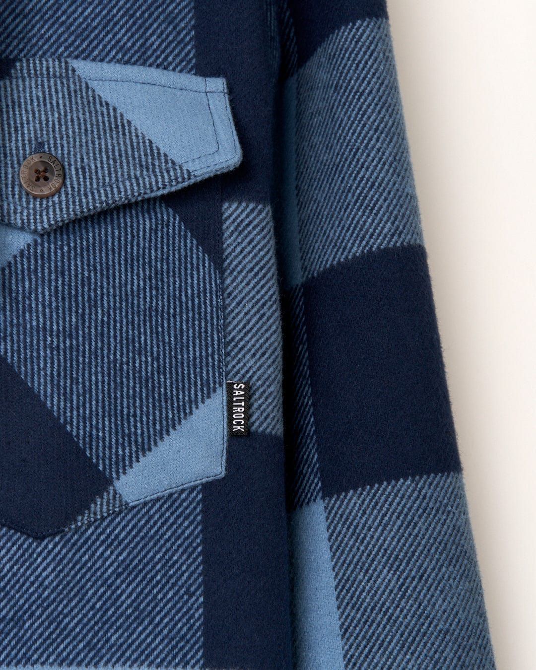 Close-up of a Saltrock Beale - Mens Hooded Long Sleeve Shirt - Blue with a visible brand label.