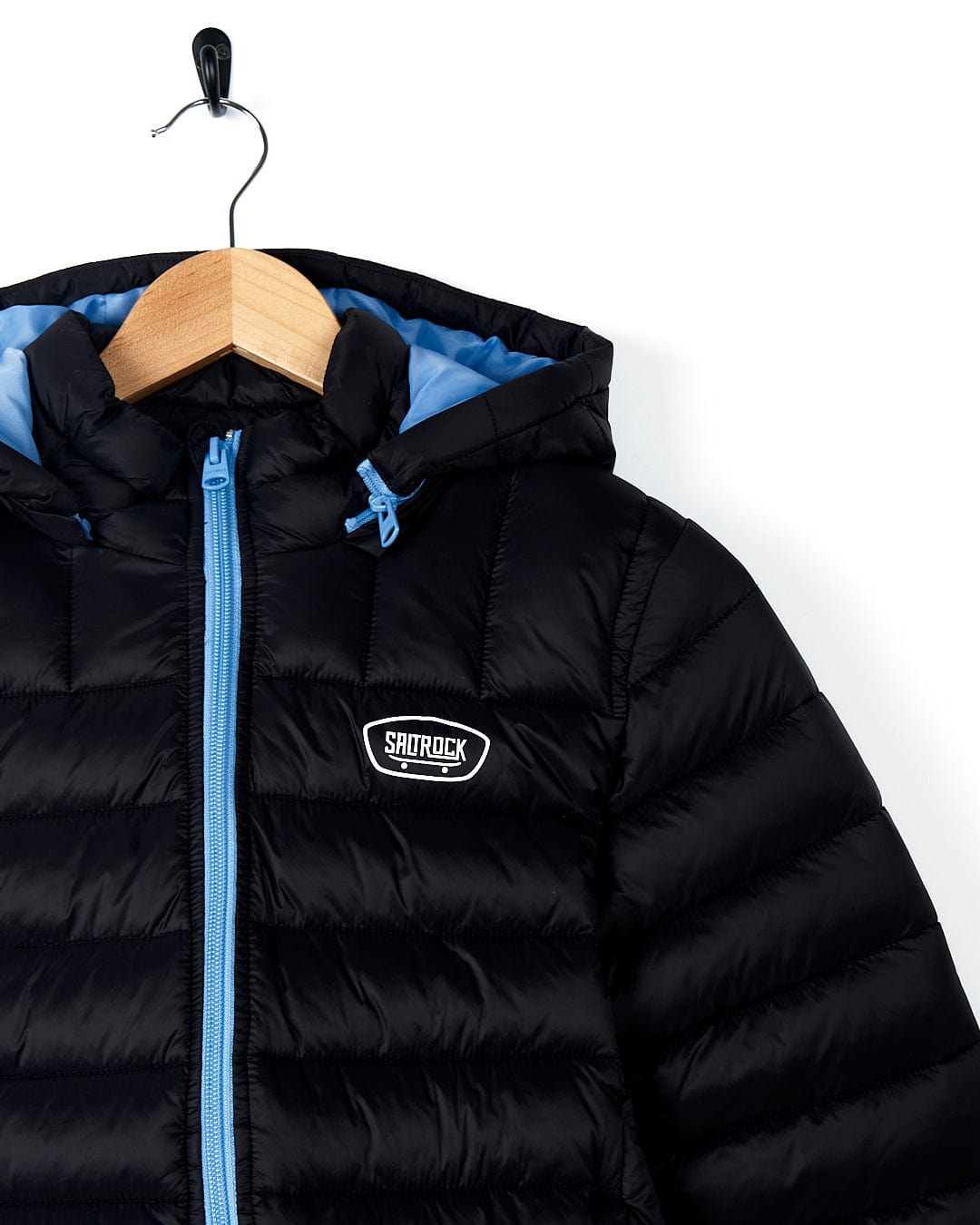 A Saltrock Beau - Kids Puffer Jacket - Black, both warm and stylish, hanging on a hanger.