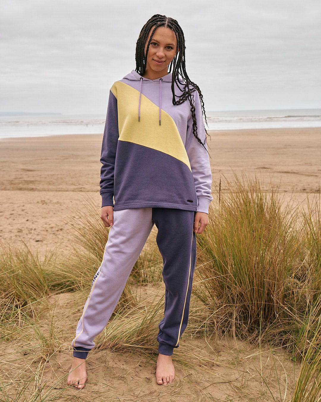 A woman in a Saltrock Betty - Womens Jogger - Light Purple hoodie standing on the beach.