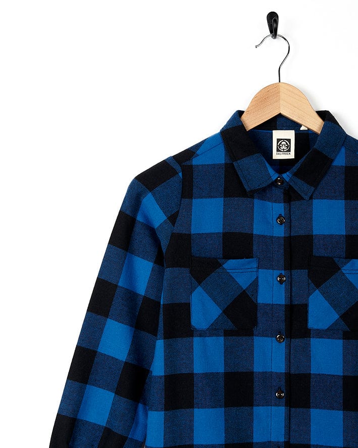 A blue and black flannel Saltrock Birdie Girls Check Shirt Dress hanging on a hanger.