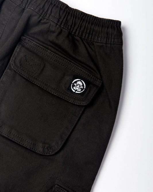 Close-up of Saltrock Bora Bora - Kids Cargo Trousers - Cargo - Dark Grey featuring cargo style pockets with button flaps and a patch with a skull design. An elasticated waist is visible at the top.