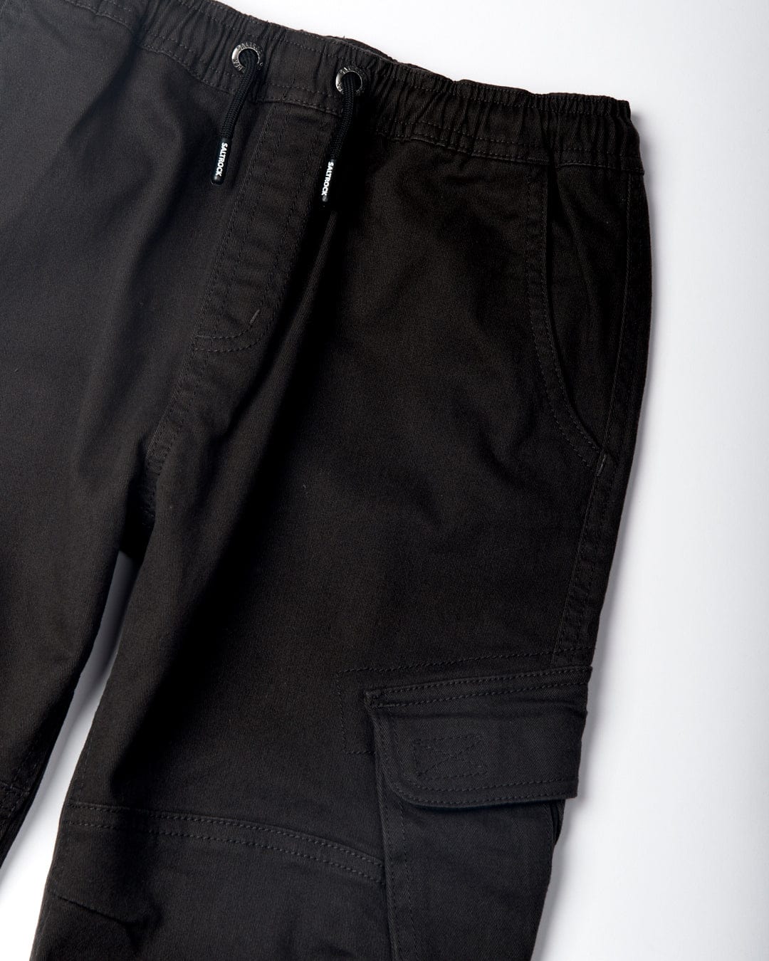 Close-up of Bora Bora - Kids Cargo Trousers - Cargo - Dark Grey by Saltrock featuring an elasticated waist with drawstrings and a side cargo style pocket with a flap.