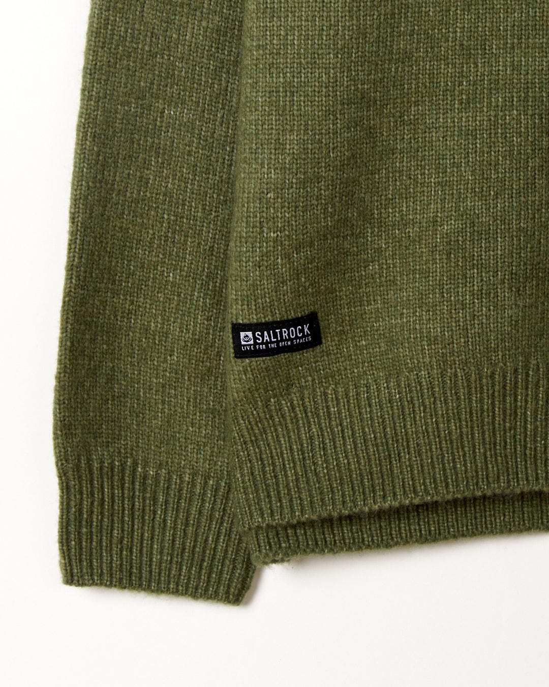 Close-up of a soft, green Saltrock sweater's sleeve with brand label.