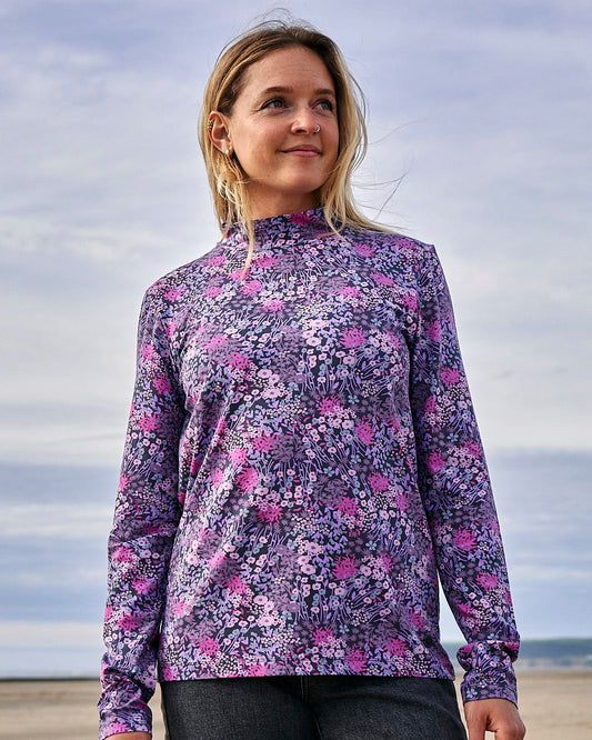 A woman wearing a Saltrock Brooklyn - Womens Long Sleeve T-Shirt - Purple with a ditsy floral print standing on the beach.