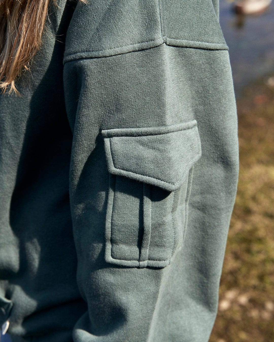 A girl wearing a green Saltrock Celeste - Womens Pop Hoodie - Dark Green with a pocket and drawstring hood.