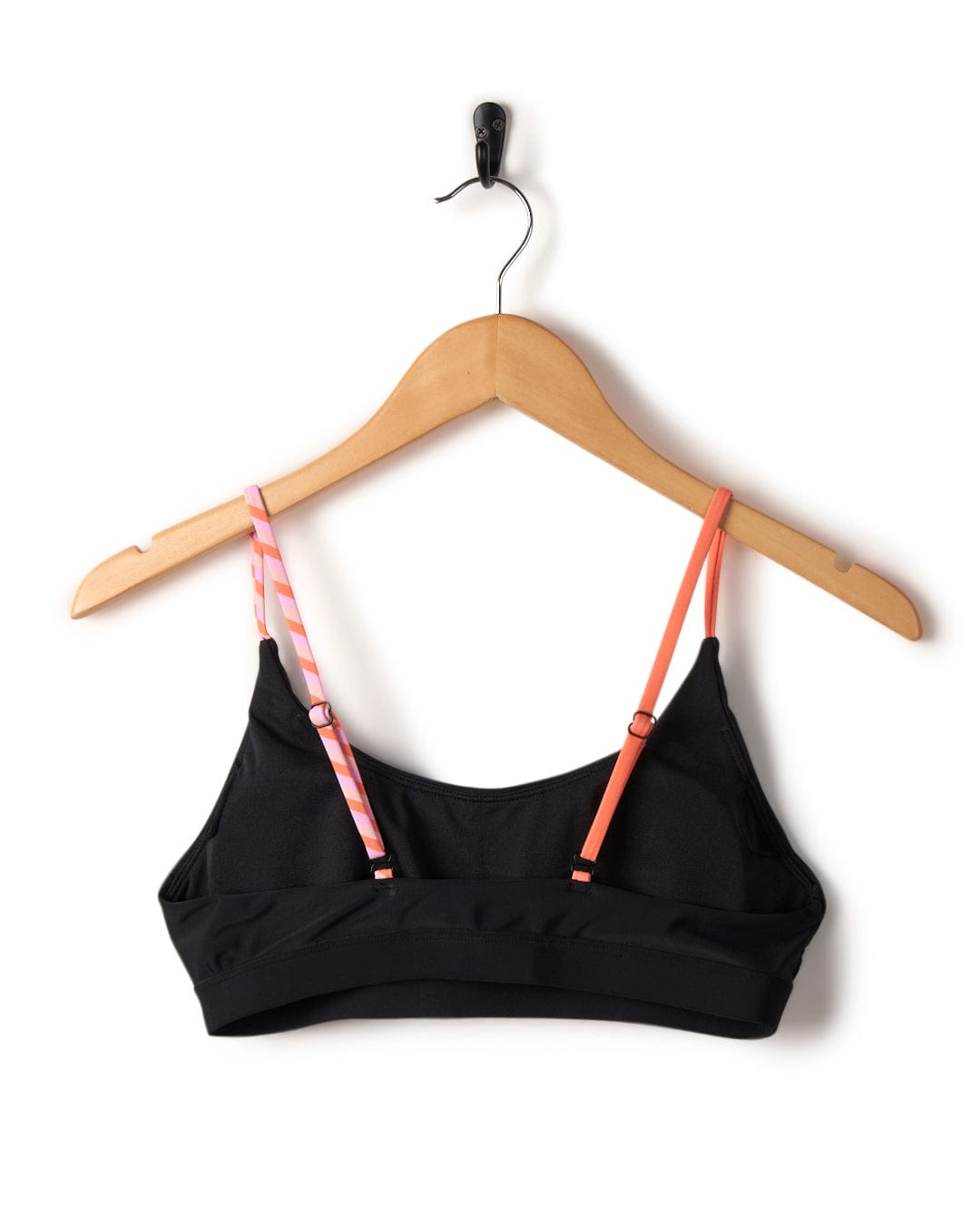 Black Cleo - Recycled Womens Retro Bikini Top with adjustable straps hanging on a wooden hanger, featuring pink and white striped straps, isolated on a white background. Brand: Saltrock