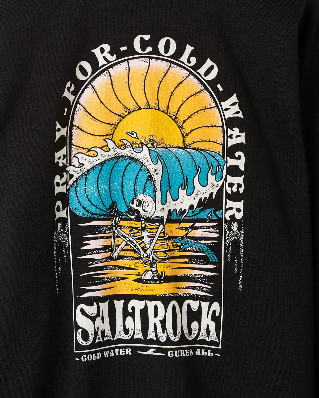 Graphic print on an Cold Water oversized black T-shirt featuring a skeleton surfing a large wave with the text "Pray for Cold Water" and "Saltrock" above and below the image.