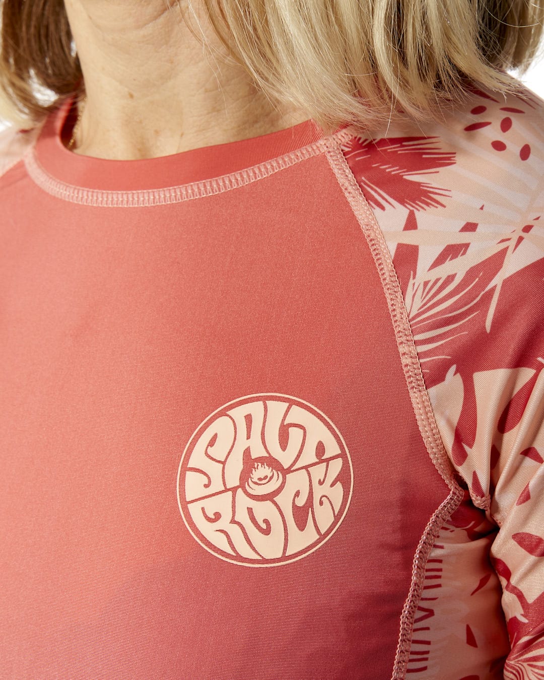 A woman wearing a Saltrock Coraline - Womens Long Sleeve Rashvest - Coral.