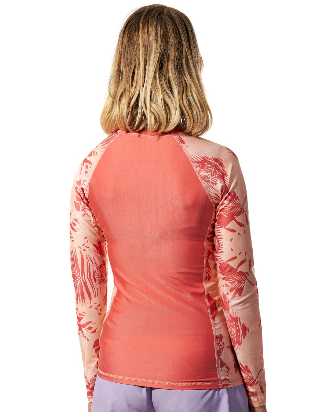 The woman is wearing a Saltrock Coraline - Womens Long Sleeve Rashvest - Coral.