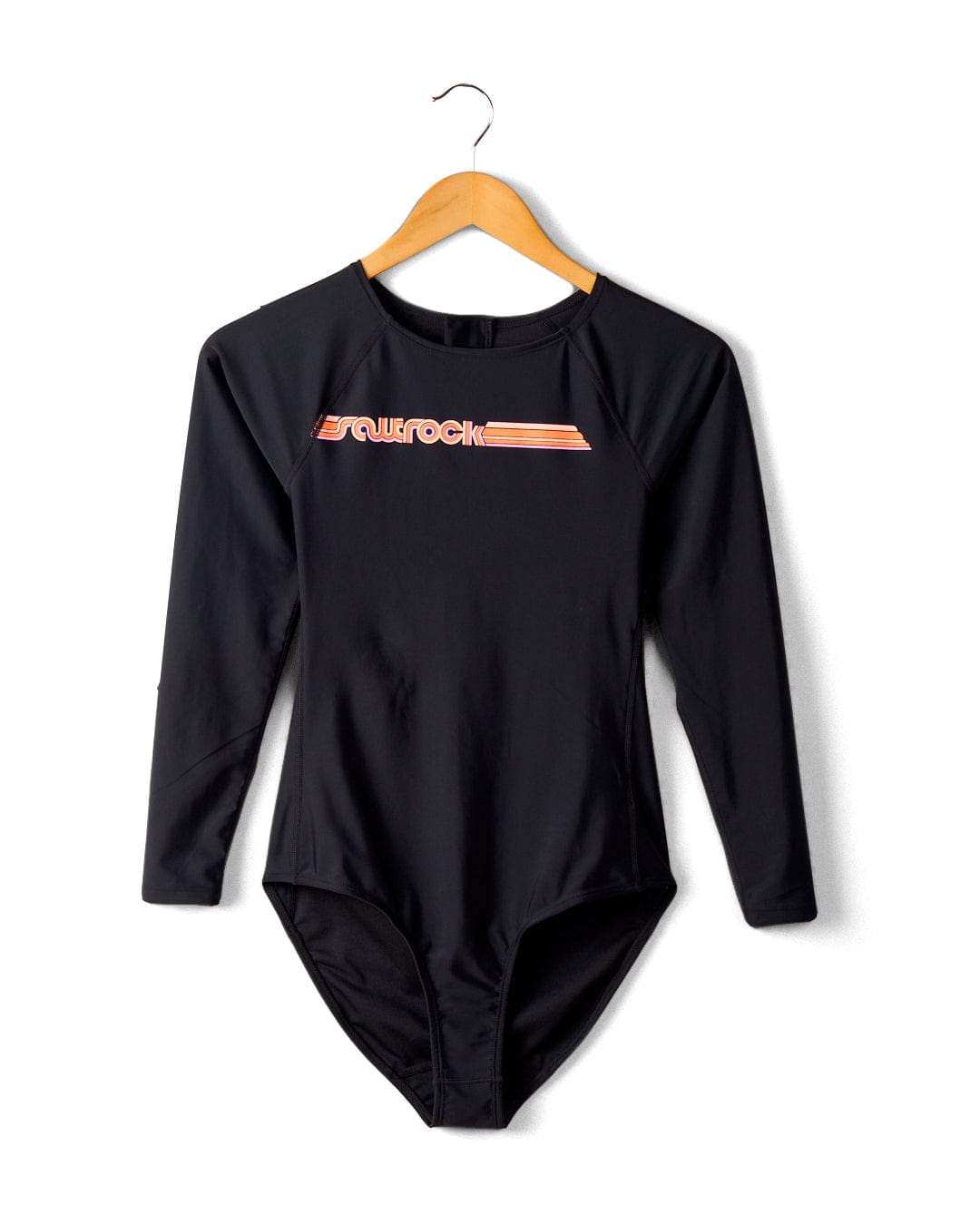 A Saltrock Cora Retro - Recycled Womens Long Sleeve Swimsuit in Dark Grey with 'surfrock' printed in orange and white on the chest, hanging on a wooden hanger against a white wall.