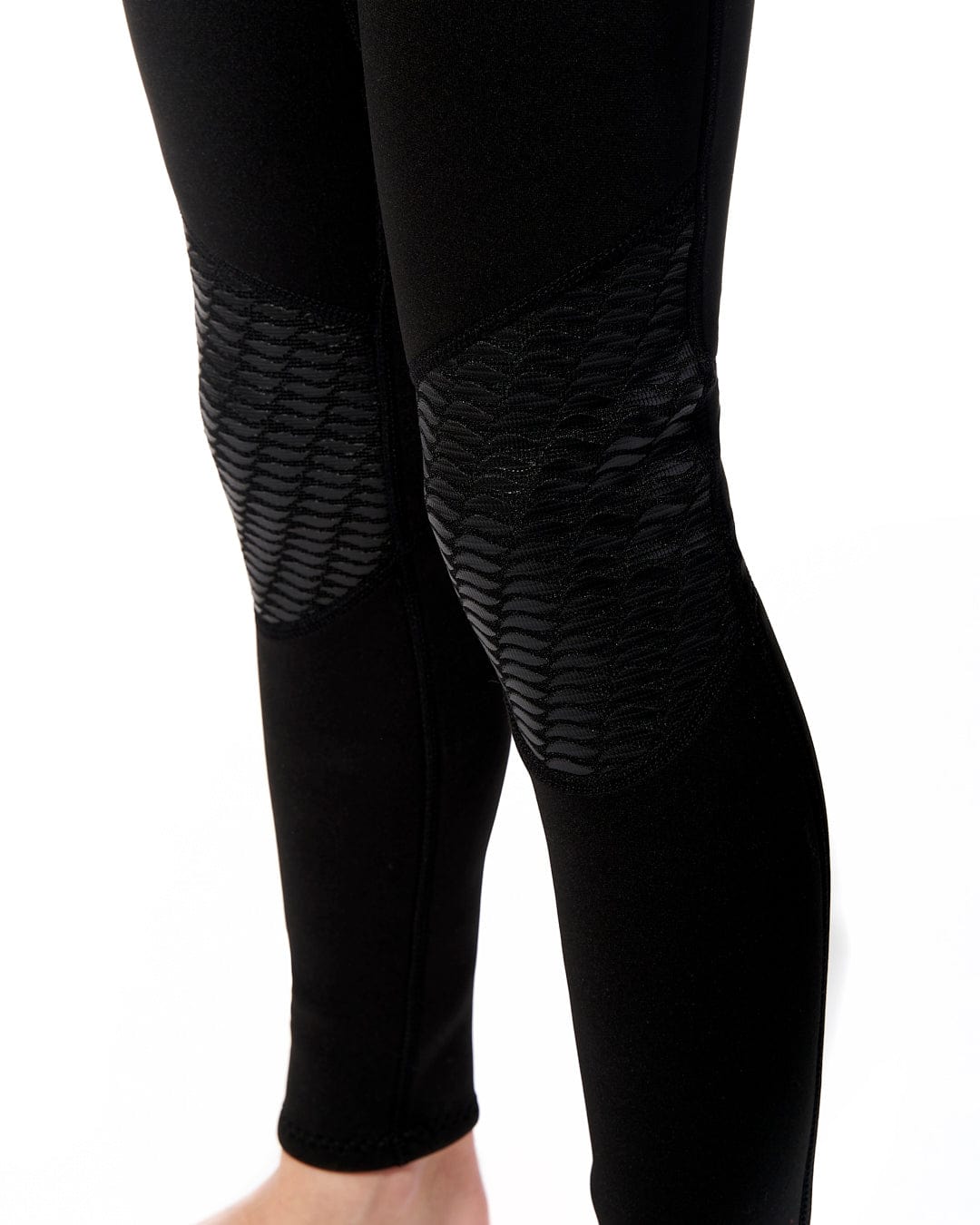 The legs of a woman wearing Saltrock Core - Kids 3/2 Full Wetsuit - Black/Red leggings.