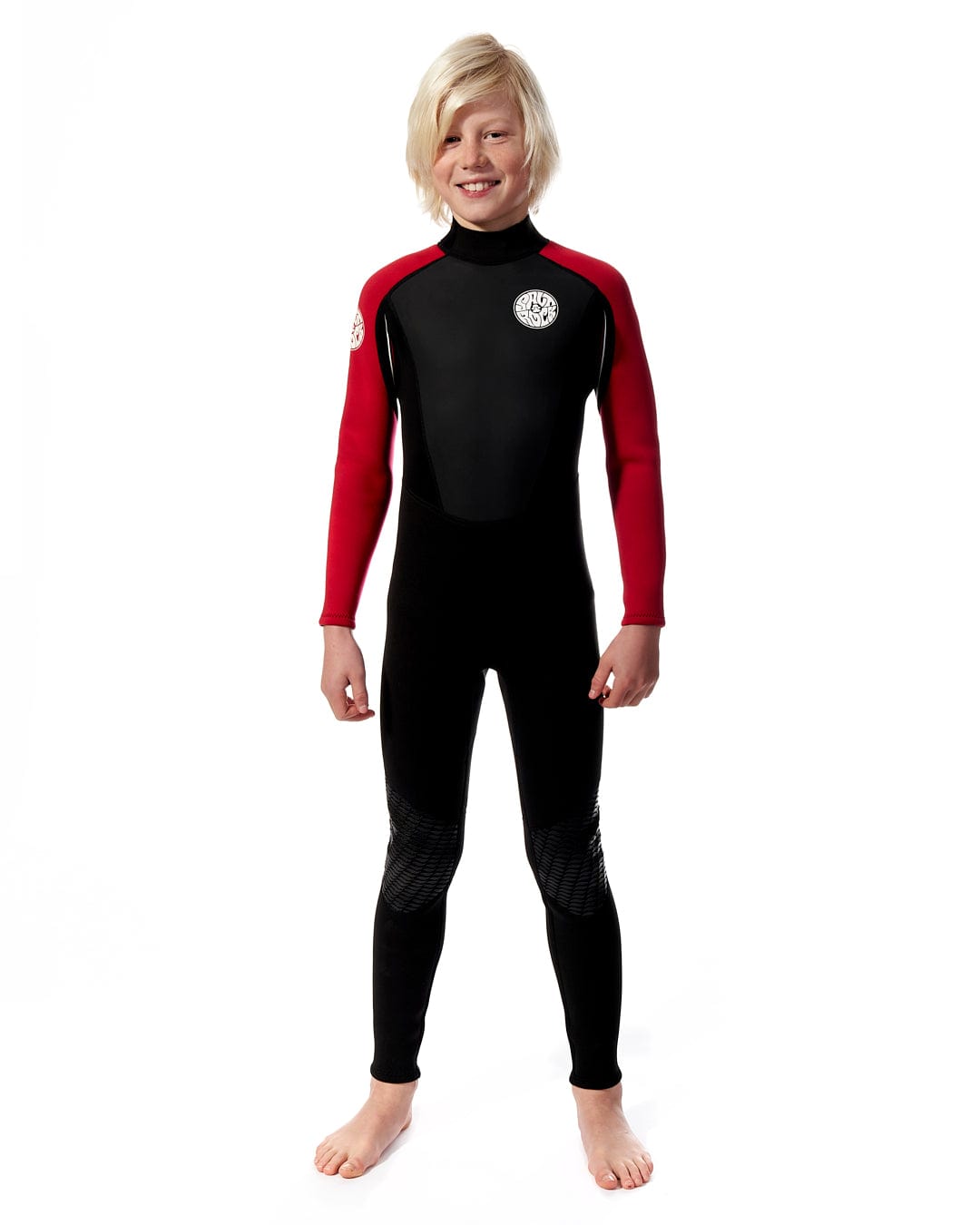 A young boy wearing a Saltrock Core - Kids 3/2 Full Wetsuit - Black/Red.