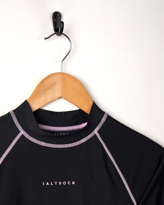 A Saltrock black Core - Recycled Womens Long Sleeve Rashvest t-shirt featuring flat locked stitching, displayed on a wooden hanger against a white background.