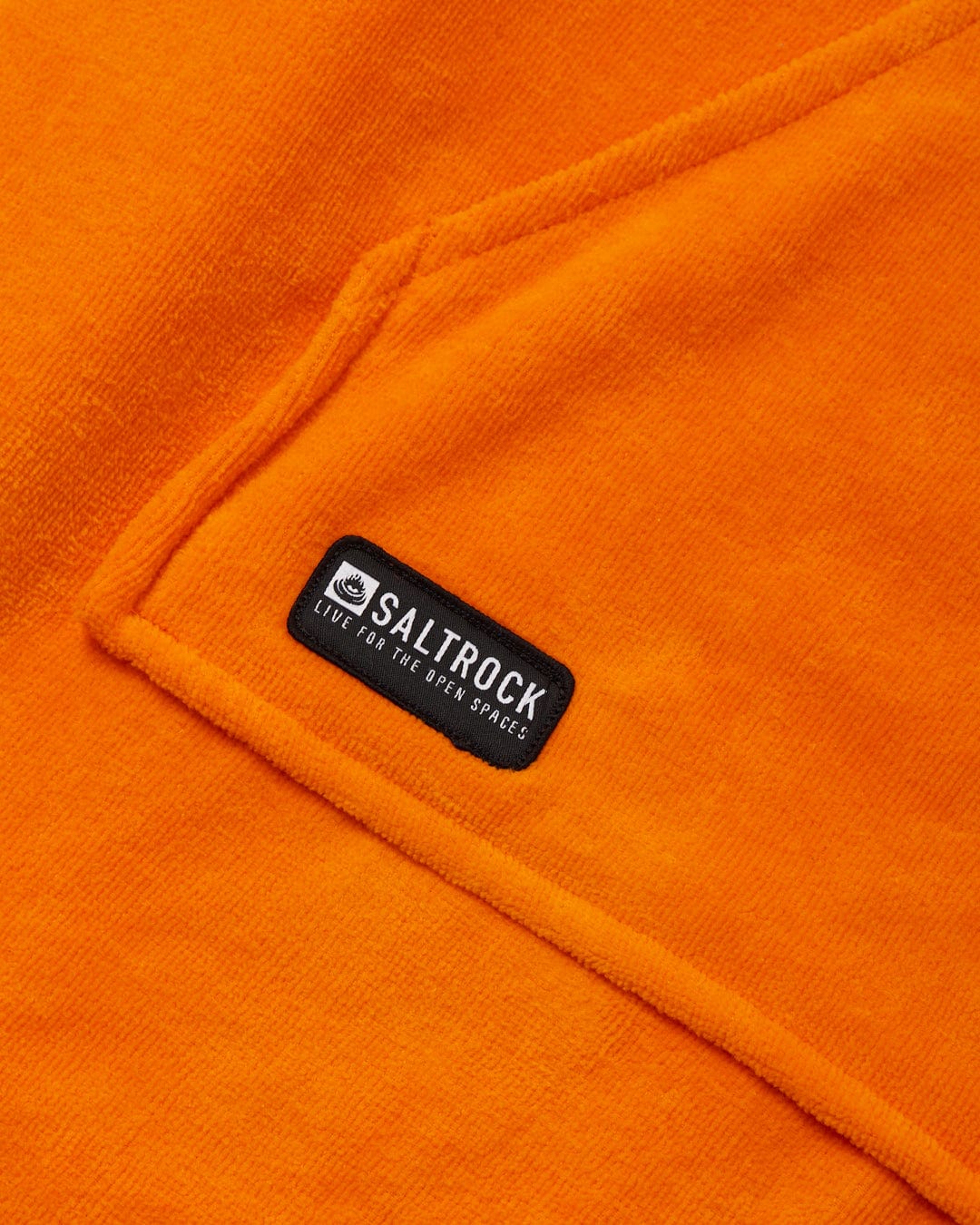 Close-up of a flamehead graphic on a Saltrock Corp Changing Towel - Orange label on an orange fabric made of fast-drying cotton towelling material.