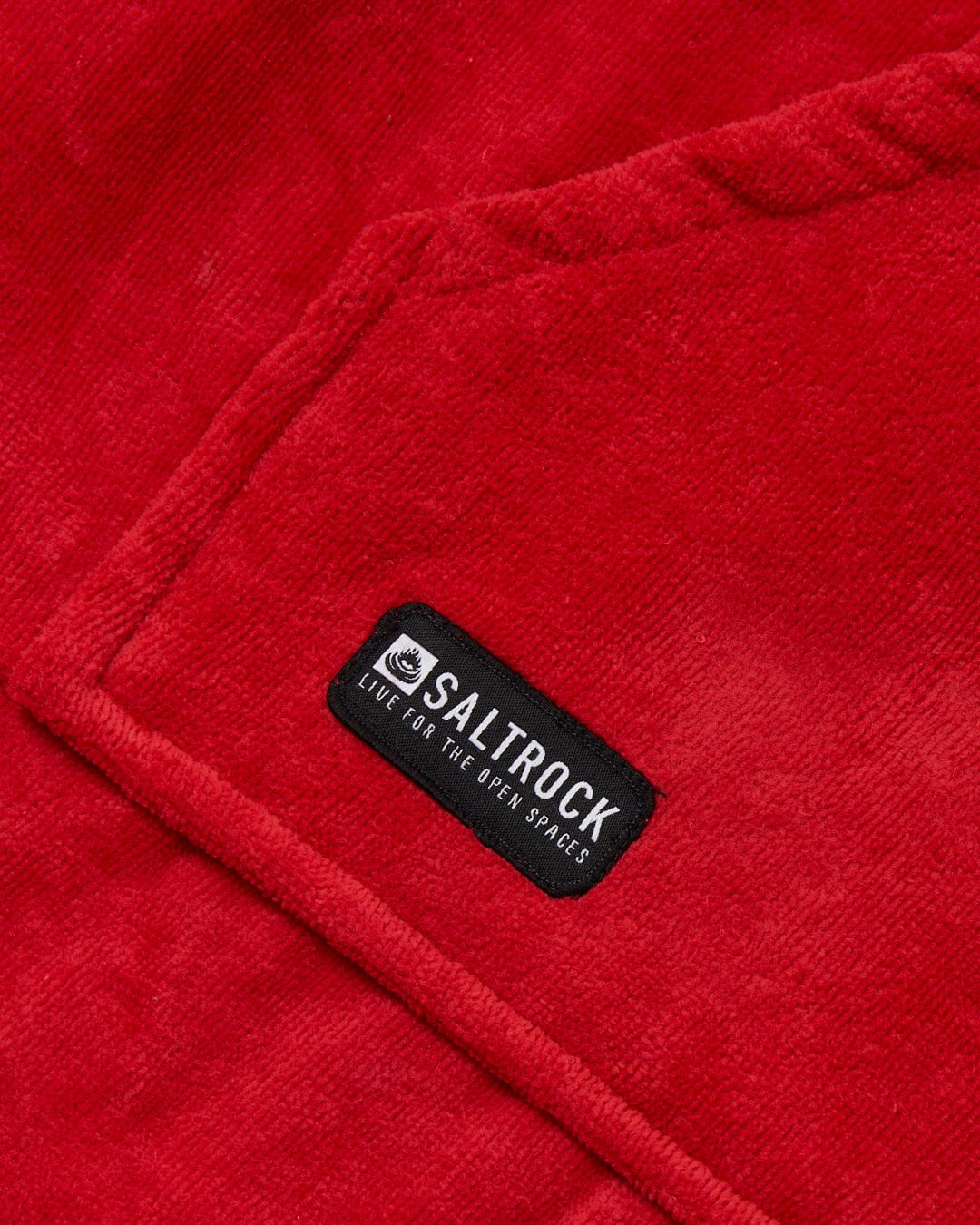 Close-up of a red, absorbent cotton towel with a black Saltrock brand label.