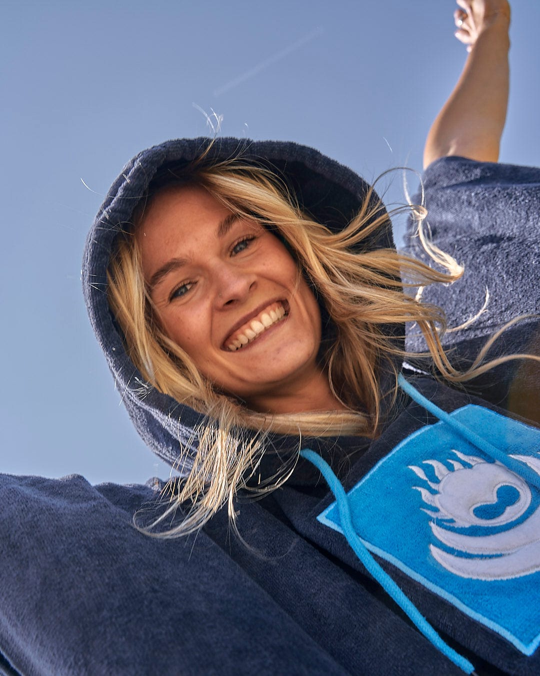 A woman wearing a blue Saltrock hoodie with a blue Saltrock logo.