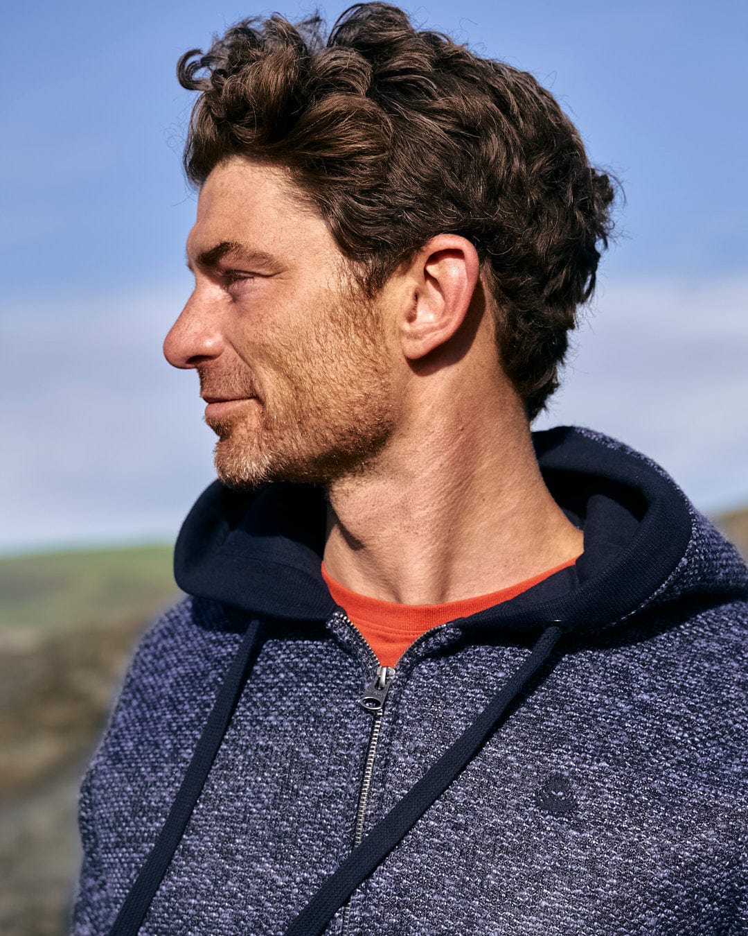 A man wearing a Saltrock Dillan - Mens Lined Hoodie - Dark Blue, looking at the ocean.