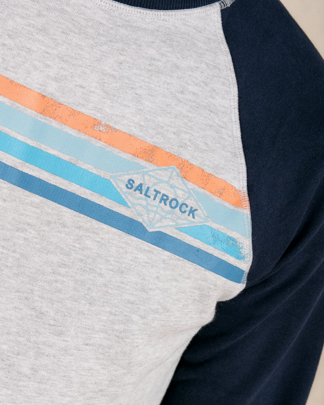 Close-up of the Saltrock Dimensions Stripe men's sweat featuring a crew neck, navy raglan sleeves, grey front with orange and blue stripes, and Saltrock branding.