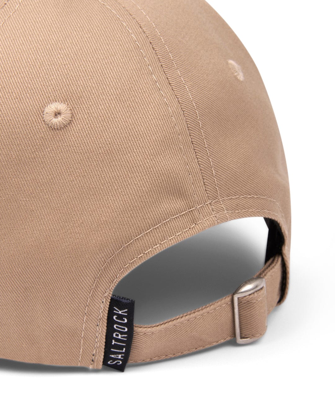 Close-up of a cream Dockyard adjustable baseball cap with a Saltrock badge and a metallic buckle.