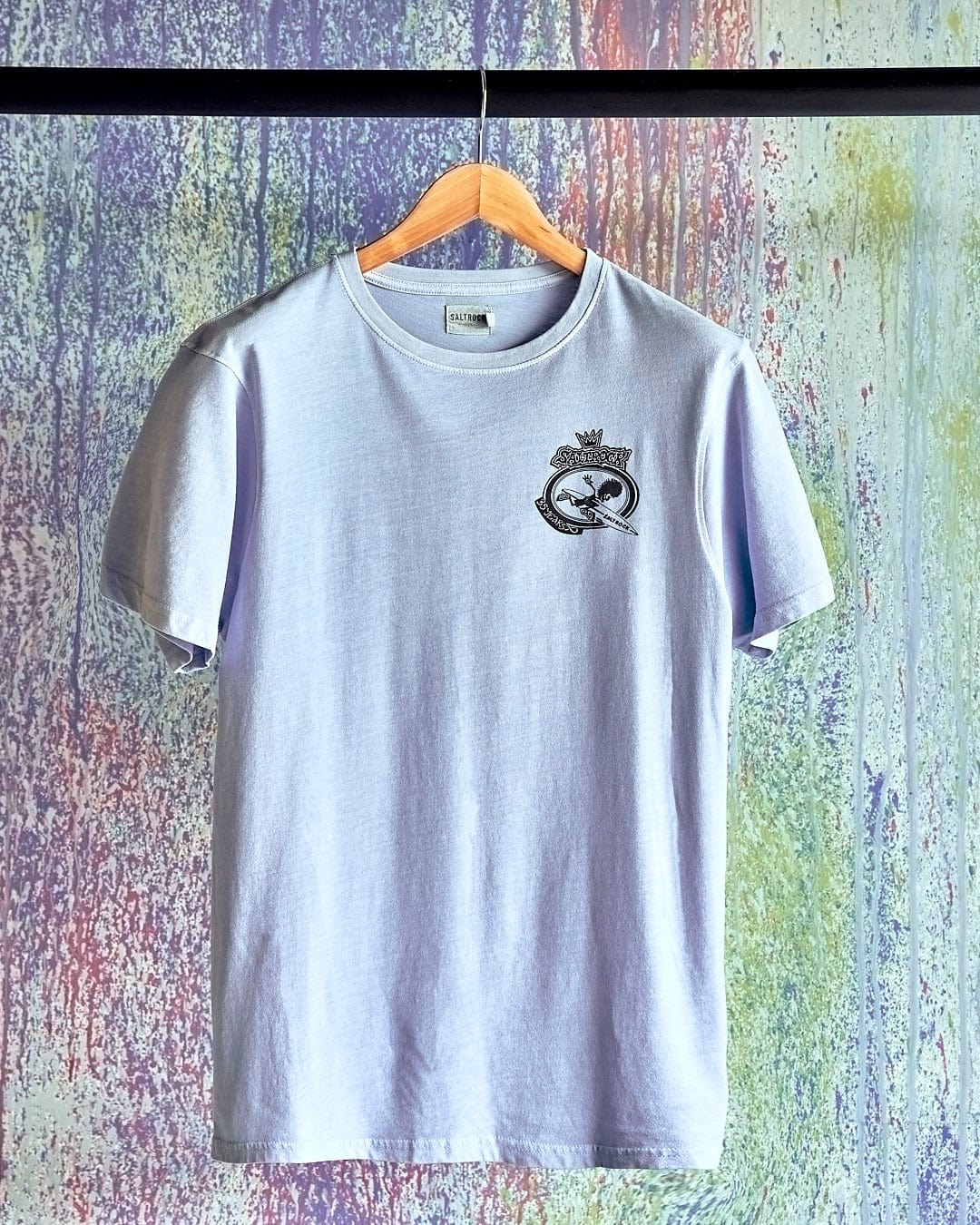 A Saltrock Dolphin - Limited Edition 35 Years T-Shirt hangs on a colorful wall.