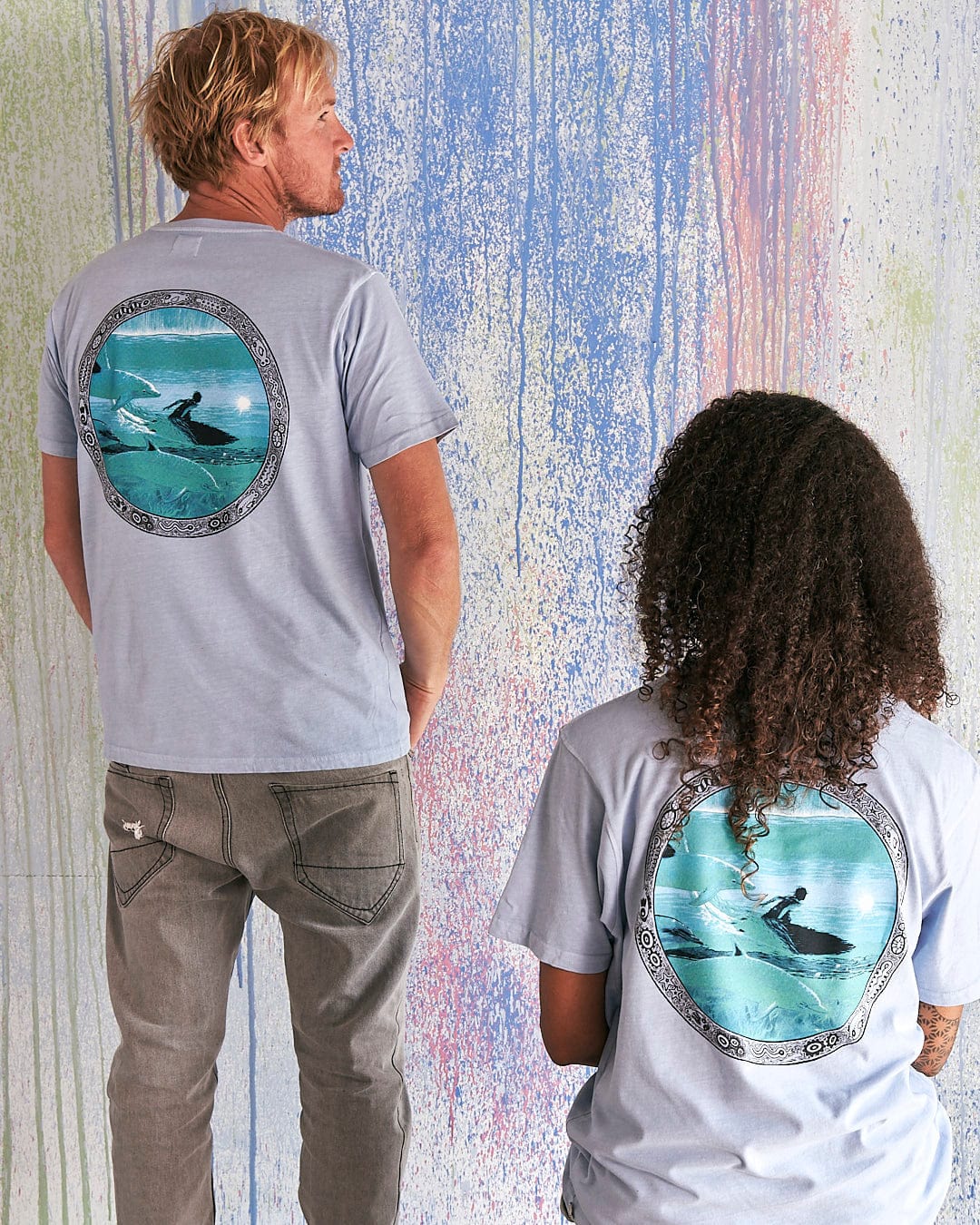 A man and woman standing next to each other wearing Saltrock's Dolphin - Limited Edition 35 Years T-Shirts.