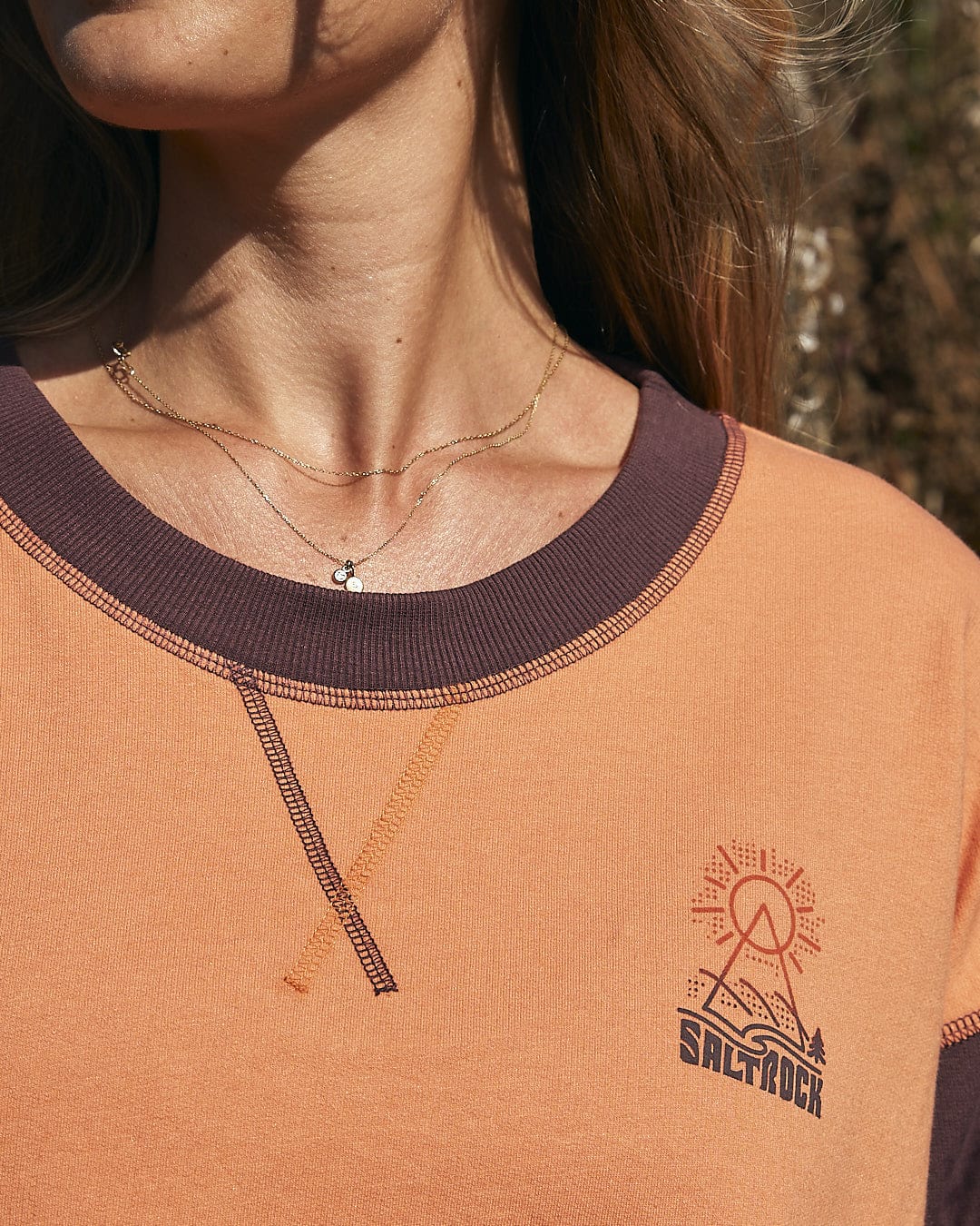 A woman in a stylish and comfortable Saltrock Elissa - Womens Boxy Sweat - Orange t-shirt, wearing a necklace.