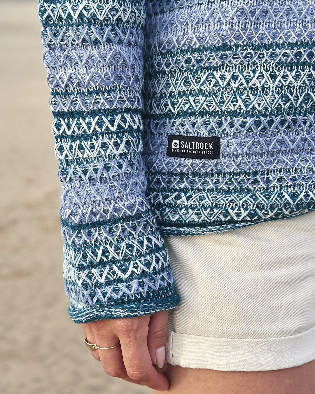 A woman wearing a Saltrock Erin - Womens Hooded Knit - Light Green sweater on the beach.