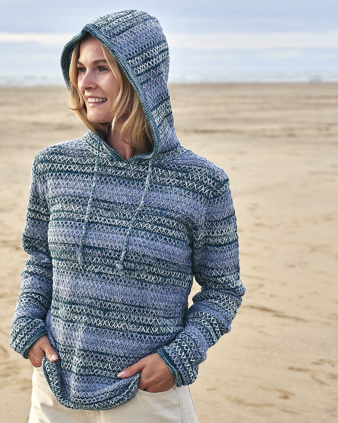 A woman wearing a Saltrock Erin - Womens Hooded Knit - Light Green on the beach.