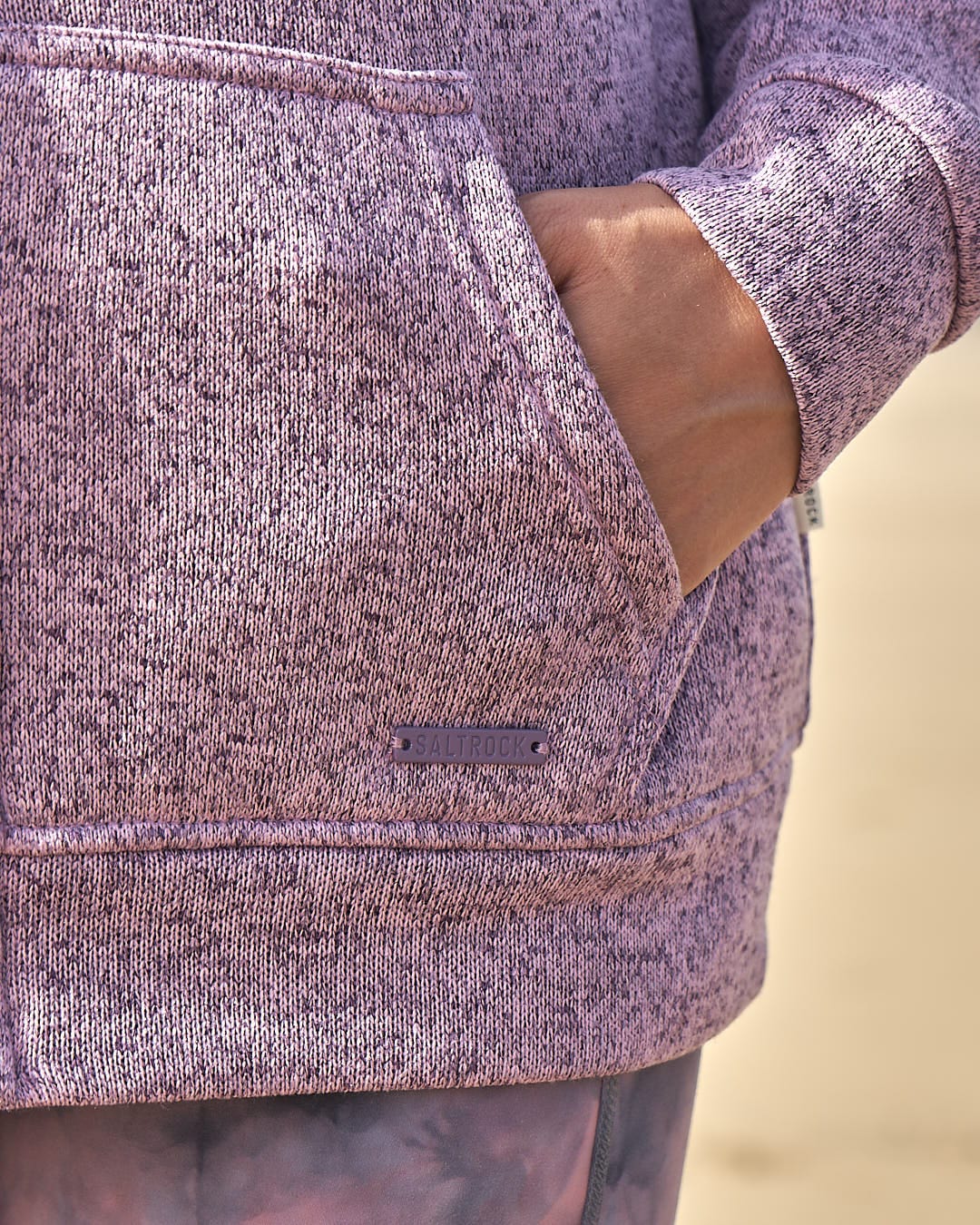 A woman wearing a Saltrock Farley - Lined Zip Hoodie - Purple on the beach.