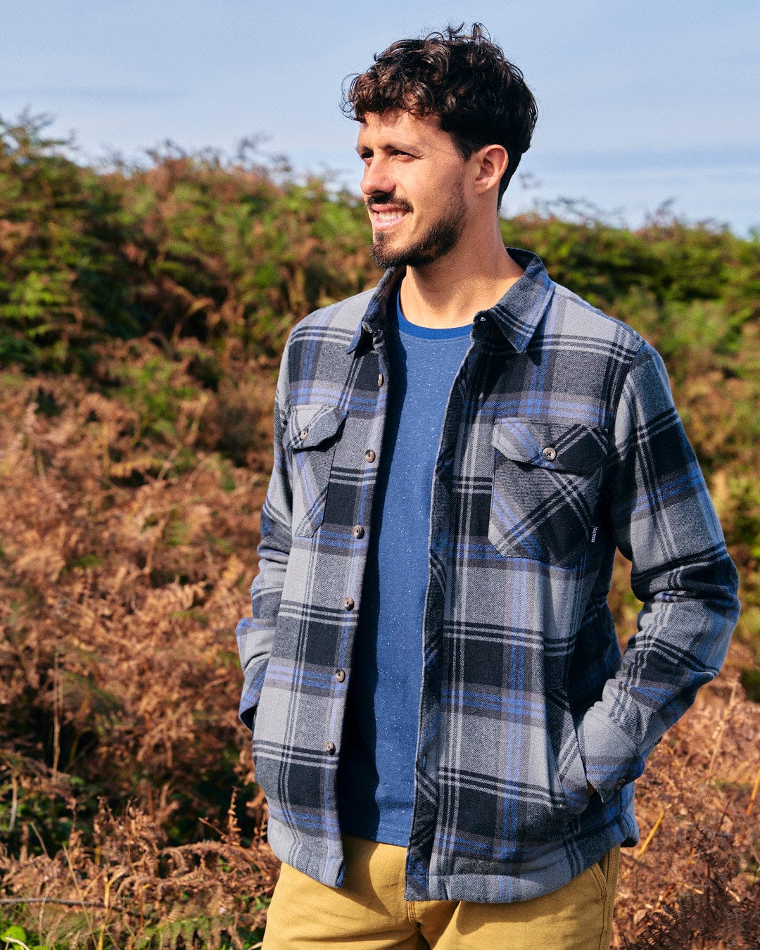 A stylish man in a warm Woody - Mens Sherpa Lined Shacket - Grey by Saltrock standing in a field.