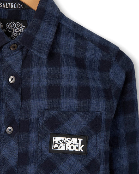 Close-up view of a blue and black check print shirt with a 'Saltrock Farrow' brand label on the pocket.