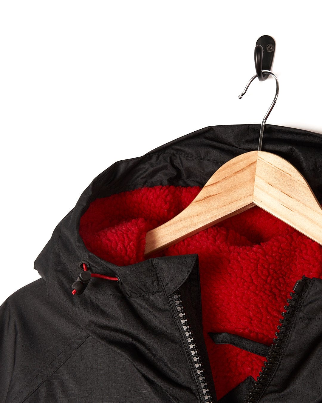A Saltrock Recycled Changing Robe - Black/Red, made from recycled materials, is partially unzipped and hanging on a wooden hanger against a white background.