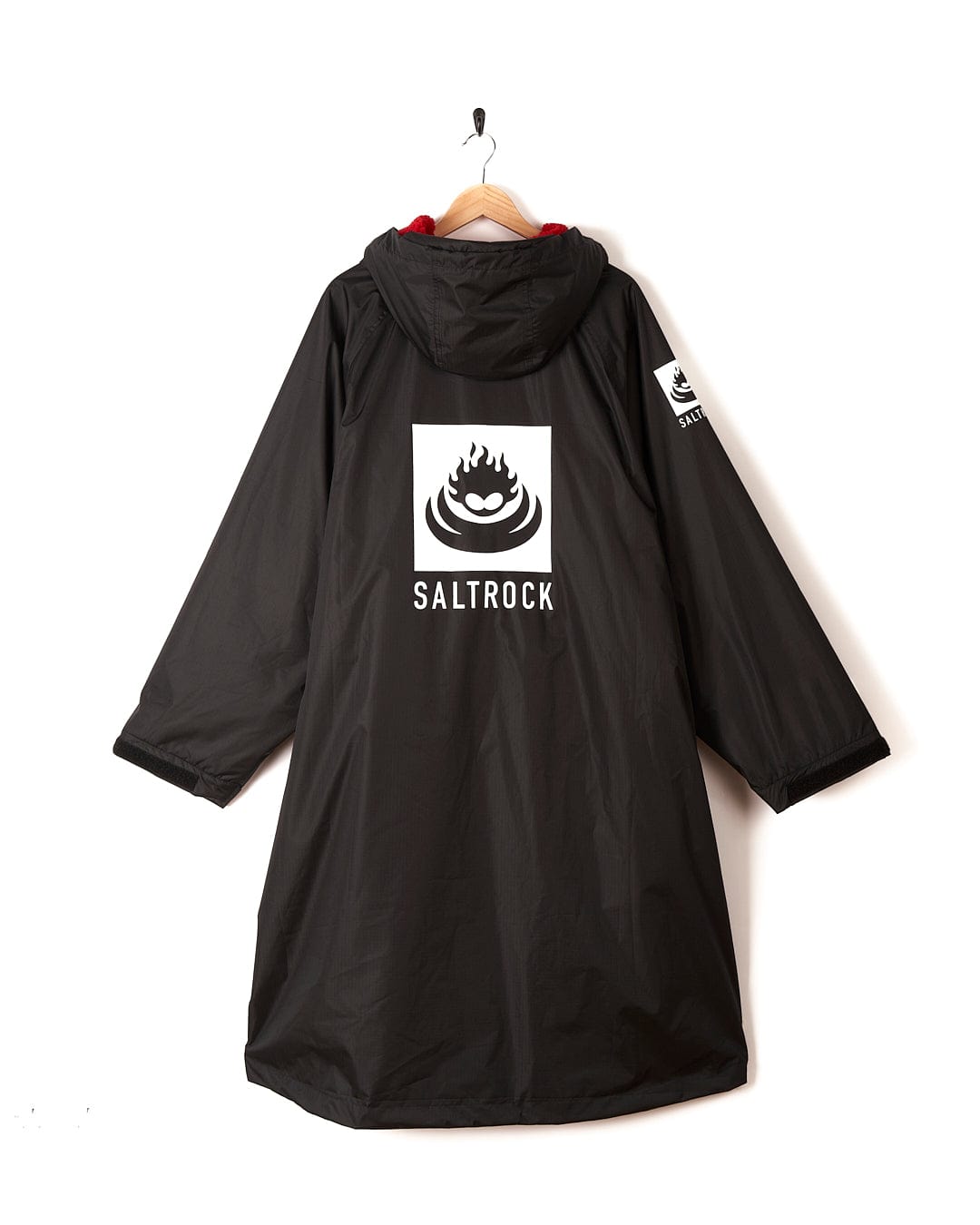 Recycled Changing Robe - Black/Red with a hood, crafted from recycled materials, featuring a white Saltrock logo and "Saltrock" text on the back, hanging on a hook against a white background.
