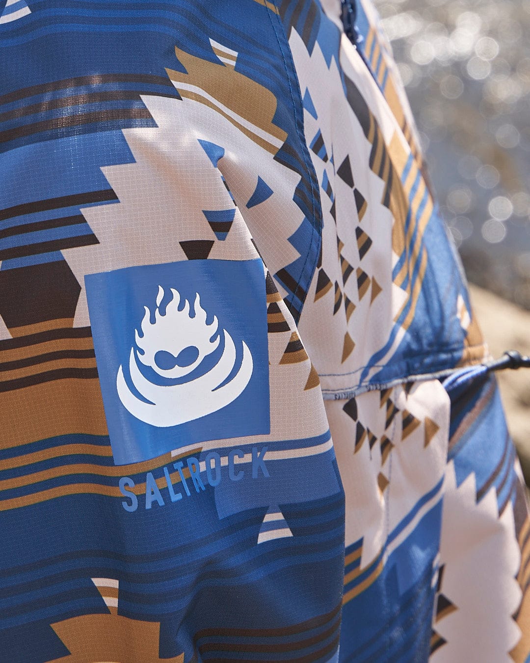 A blue and brown Four Seasons Changing Robe - Aztec with the word salwa on it. (Brand Name: Saltrock)