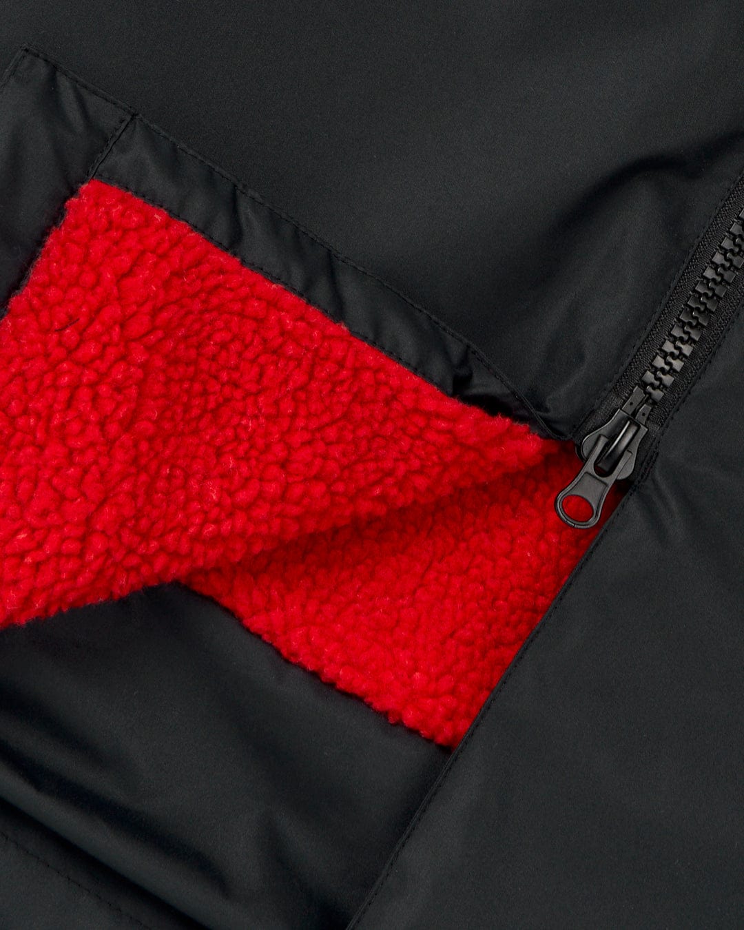 Close-up of a Saltrock Recycled Kids Changing Robe - Black/Red made from recycled materials, with an open zipper revealing a red fleece lining inside.