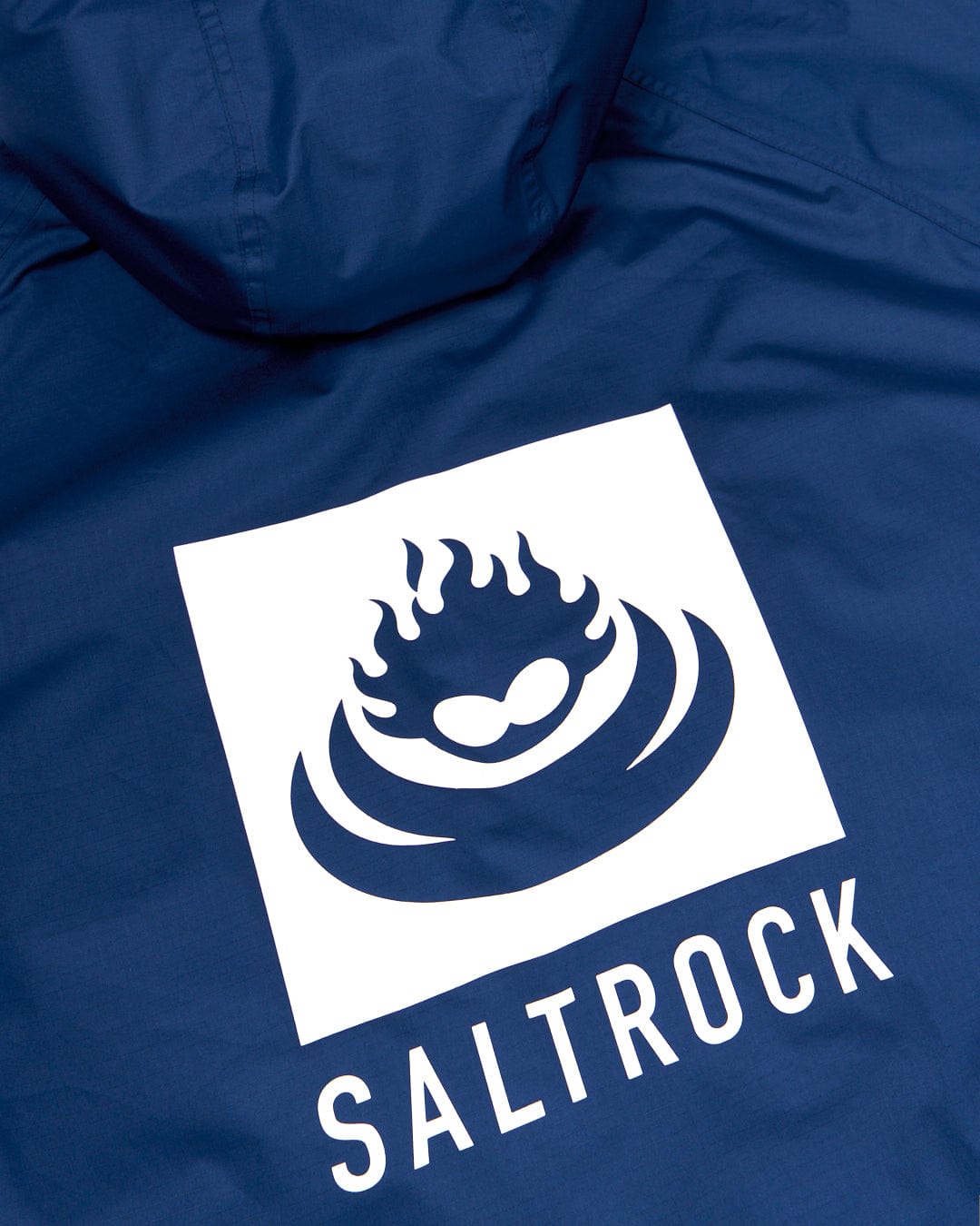 Close-up of a blue jacket featuring the white Saltrock logo, which includes a stylized wave and flame design with text "SALTROCK" below, reminiscent of their Changing Robe - Blue collection by Saltrock.
