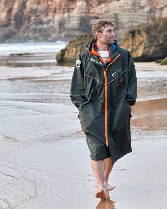 Man walking on the beach in a long Saltrock Recycled Four Seasons Changing Robe - Green/Aztec.