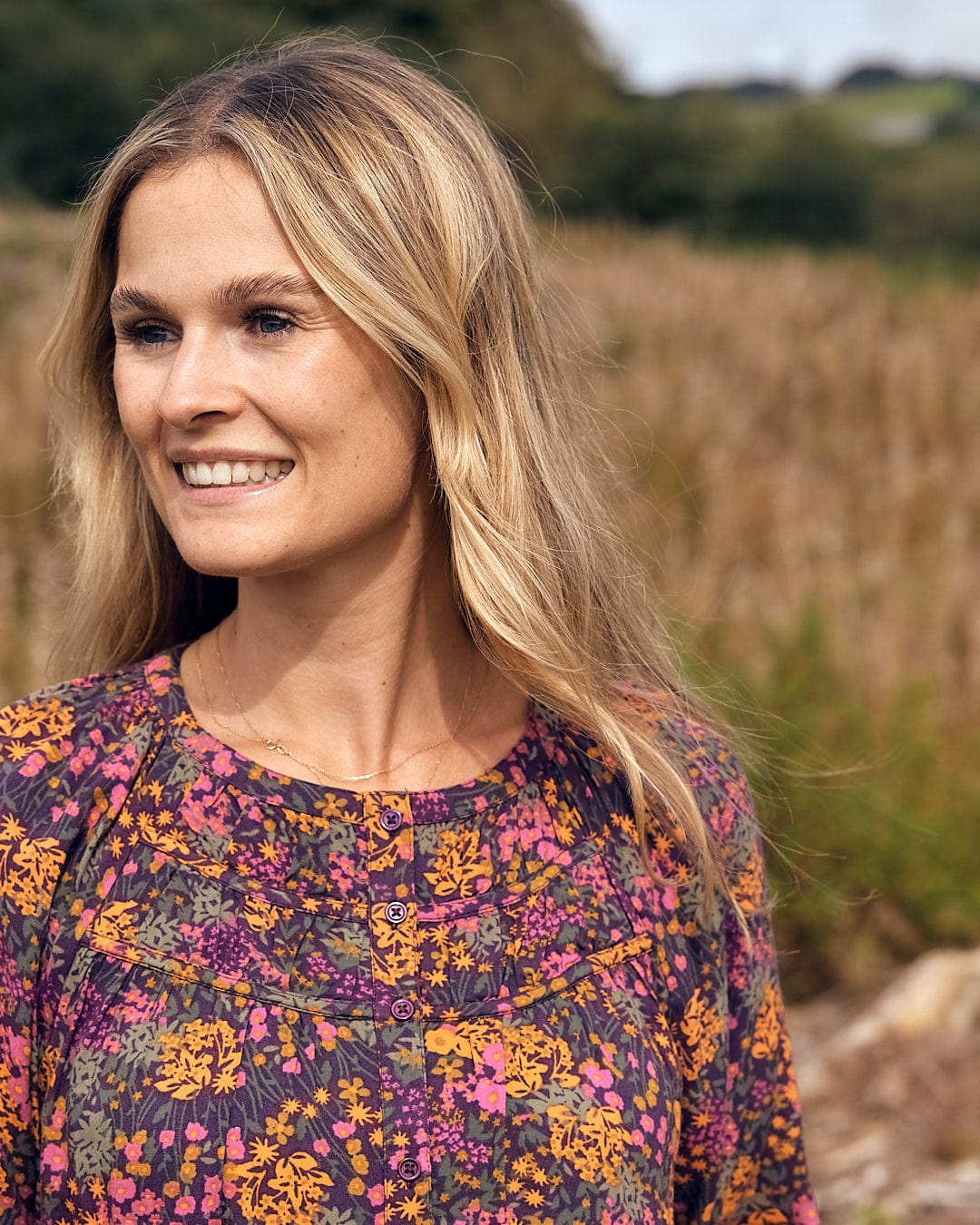 A woman in a Saltrock Garnet - All Over Print Blouse - Orange standing in a field.